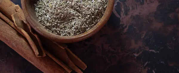  Kahverengi ahşap arka plan, yatay resim. Durgun hayat. Tahta kase, anason tohumları ve tarçın çubukları.. 