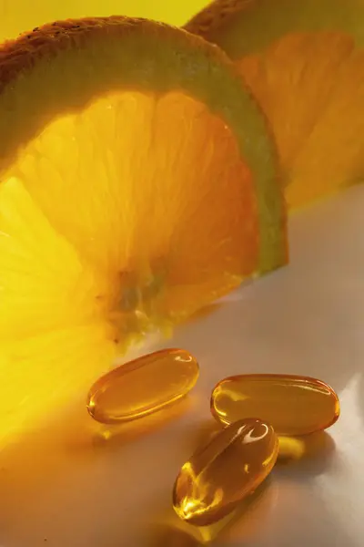 Dikey portakal arka planı. Destekleme promosyonu için pankart. Sağlıklı bir diyet için gerekli takviyeler. Yumuşak kapsüllerde C vitamini.. 