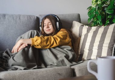 Hafta sonları kulaklıkları kanepede dinlenip müzik dinleyen mutlu, huzurlu bir kadın. Yüksek kalite fotoğraf. Bedava yaşam tarzı konsepti. Uzayı kopyala Kış rahatlama anı konsepti