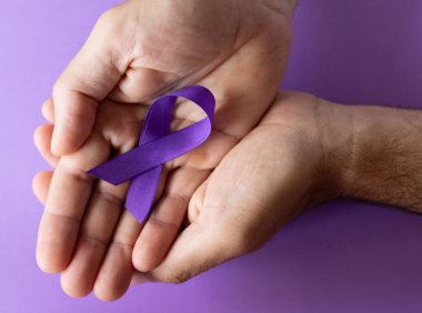 Mor arka planda Dünya Kanser Günü sembolü. Kanser koruma farkındalığı. Uzayı kopyala. Gerçek görüntü. Kanser önleme kampanyası için yatay pankart