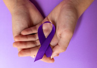 Mor arka planda Dünya Kanser Günü sembolü, umut ve dayanışmayı temsil ediyor. Uzayı kopyala. Gerçek görüntü. Kanser önleme kampanyası için yatay pankart