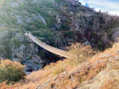 Dağlar arasında eski bir ahşap asma köprü. Turizm terfileri ve dergiler için panoramik bir arka plan. Mesaj için yer var. Gerçek fotoğraf.