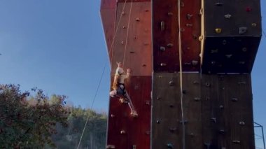 Açık hava parkında duvara tırmanan küçük bir kızın arka görüntüsü. Ekstrem spor ve kaya kavramı. Çocuk spor aktivitelerinde hareket ediyor..