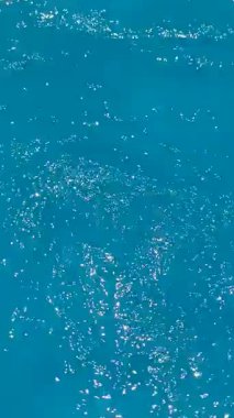 Çıplak ayaklı kadın havuz manzarasının berrak serin sularında ayaklarıyla oynuyor. Dikey 4K görüntü. Yaz ve tatil kavramları. Mesaj için boşluk.