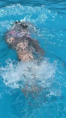 Havuzda eğlenen bir kız. Yaz seyahati ve turizm. Dikey 4K görüntü. Yaz ve tatil kavramları. Mesaj için boşluk.