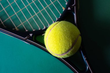 Tenis raketi ve topların üst görüntüsü yeşil arka planda. İskele kavramı. Anlaşıldı. Tenis sporu promosyonu için arka plan. Görüntüyü netleştir 