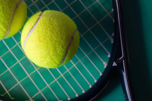 Yeşil arka planda tenis raketi ve topa yakın plan. Tenis sporu promosyonu için arka plan. Gerçek yatay resim. 