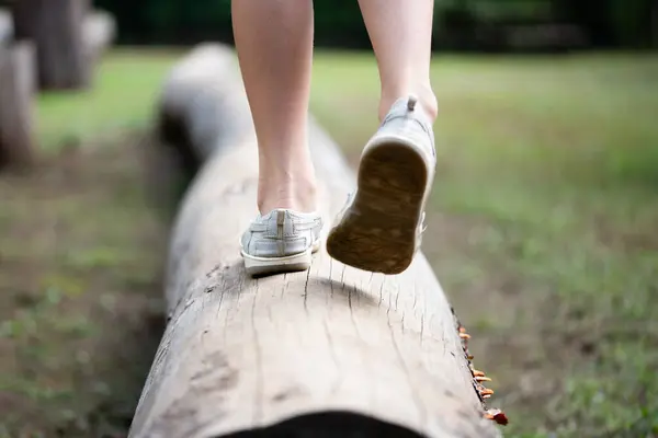 child\'s feet walking on a log