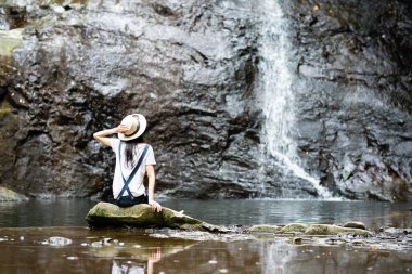 Şelalenin yanında oturan genç kadın. 