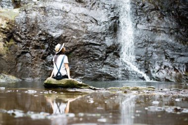 Şelalenin yanında oturan genç kadın. 