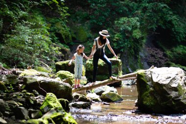 Anne ve kızı bir dağ deresinde oynuyorlar.