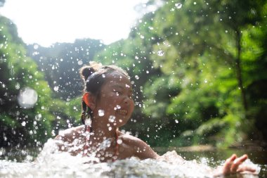 Asyalı kız nehirde suyla oynuyor.