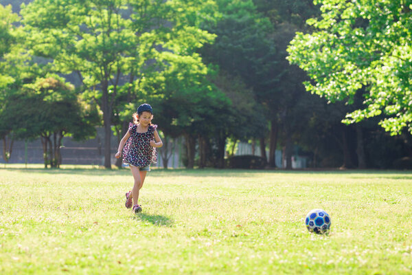 маленькая девочка играет в футбол на лужайке 