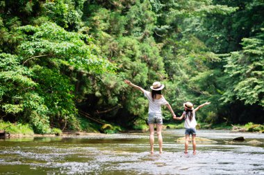 Anne ve kızı nehirde oynuyorlar.