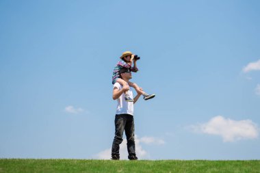 Baba ve kızı uzaktan dürbünle bakıyorlar.