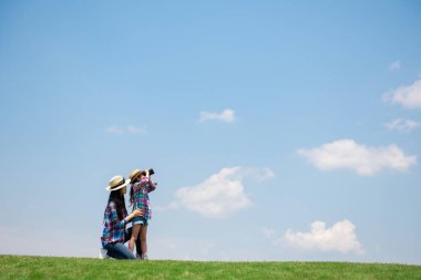 Anne ve kızı dürbünle uzaklara bakıyor. 