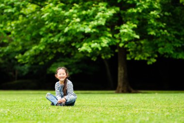 çimenlerin üzerinde oturan gülümseyen kız