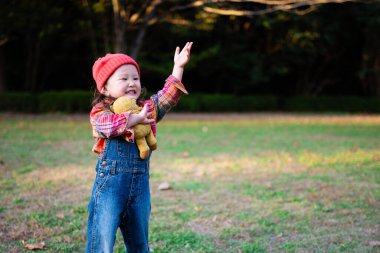 little asian girl with teddy bear  in park.