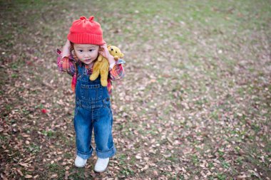 little asian girl with teddy bear  in park.