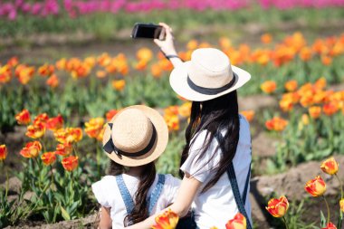 Anne ve kızı çiçek tarlasında fotoğraf çekiyor.