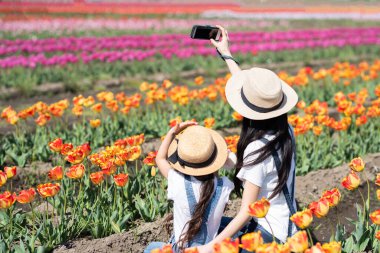Mother and daughter taking pictures in the flower field clipart