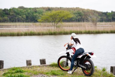 Gölün kenarında motosikletli genç bir kadın. 