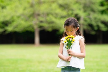 Park arka planında çiçekleri olan sevimli Asyalı kız..