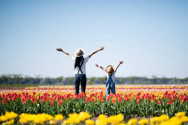 beautiful asian girl with mother  in the flower field with hands up