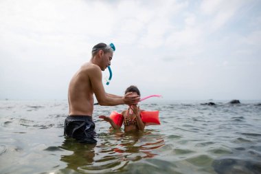 Babası kızına şnorkelle yüzmeyi öğretiyor.