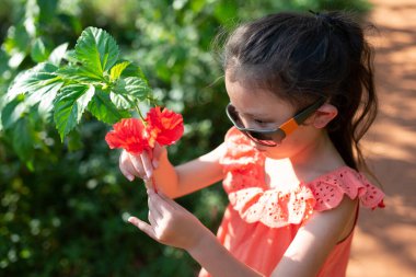Bahçede çiçek seyreden kız.
