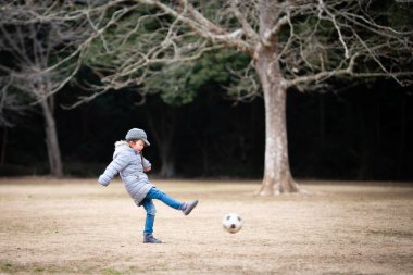 Çocuk kız parkta futbol topuyla oynuyor. 