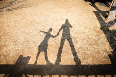 Parkta oynayan baba ve kızın gölgesi.
