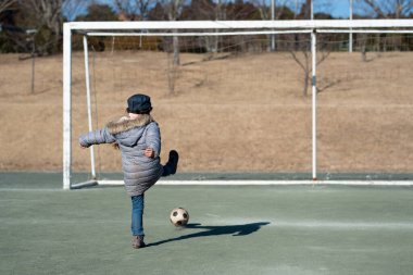 Çocuk kız parkta futbol topuyla oynuyor. 