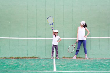 Genç kız ve anne tenis oynuyorlar.