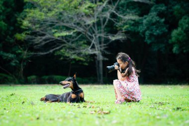 Parkta bir köpeğin fotoğrafını çeken Asyalı kız. 