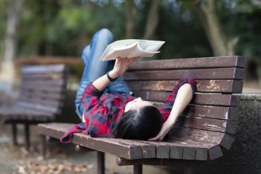 Parkta kitap okuyan Asyalı kız.