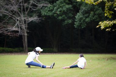 Anne ve kızı parkta egzersiz yapıyor.