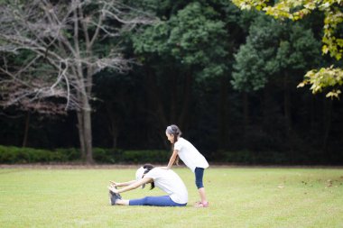 Anne ve kızı parkta egzersiz yapıyor.