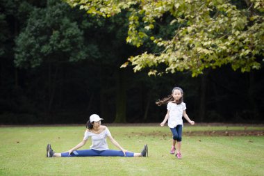 Anne ve kızı parkta egzersiz yapıyor.