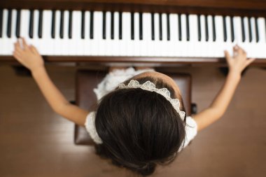 Evde piyano çalan Asyalı kız, üst manzara.