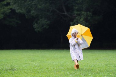 Yağmurlu bir günde şemsiyeyle yürüyen bir kız.