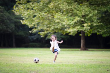 Kız futbol topuyla oynuyor.