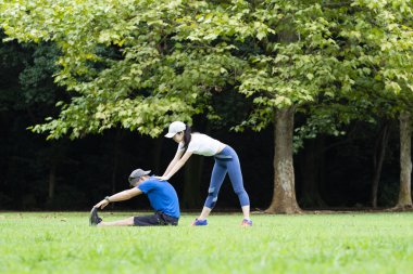 Genç Asyalı çift parkta egzersiz yapıyor.