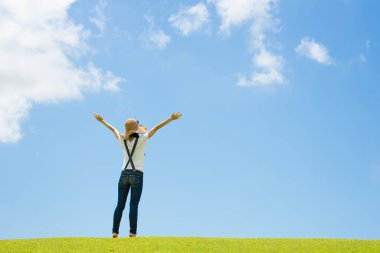 Şapkalı kadın, elleri yeşil çimlerin üzerinde duruyor. 