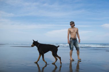 Kumsalda köpekli genç Asyalı adam. 