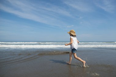 Asyalı kız sahilde eğleniyor.