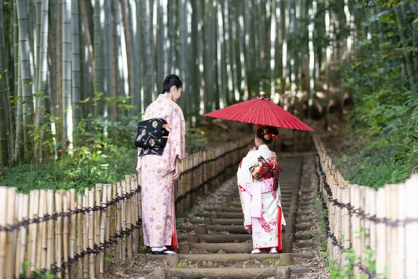 Genç Asyalı anne ve kızı bambu ormanında geleneksel Japon elbiseleri giymişler.