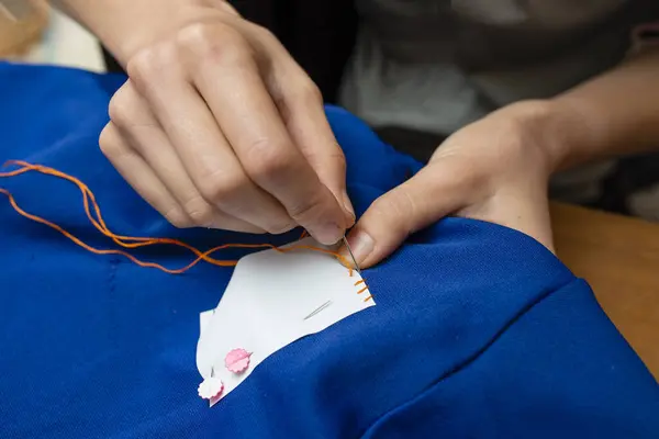 Mother sewing a name tag to a child\'s jersey