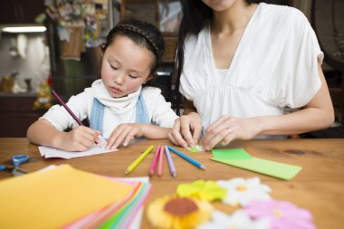 Anne ve kızı origami ile oynuyorlar.