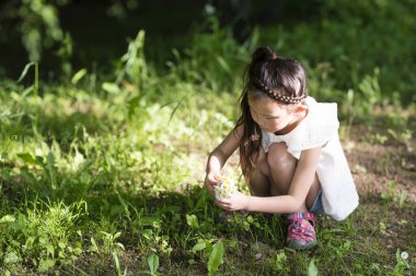 Doğada çiçek toplayan küçük bir kız